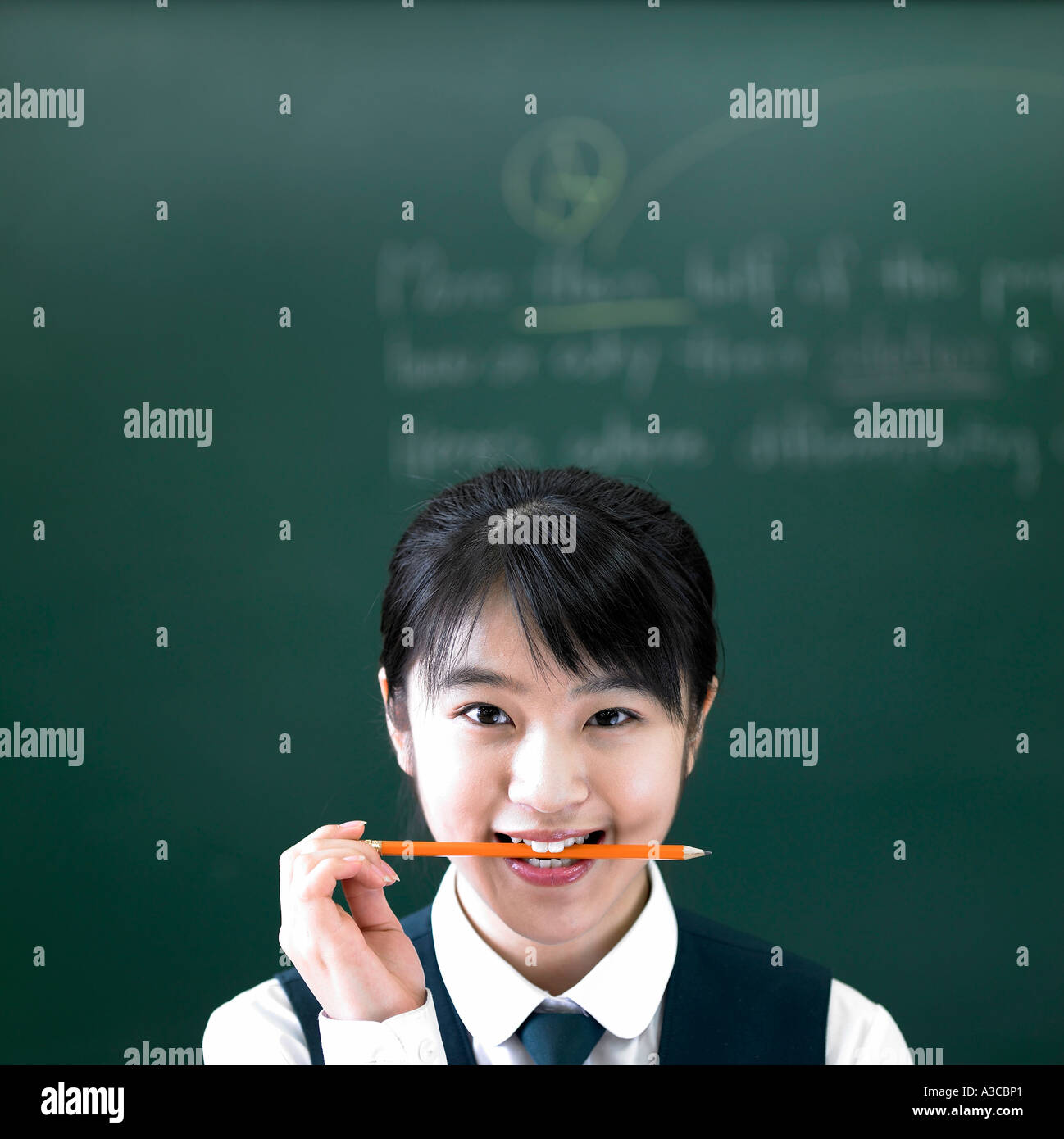 A student holding her pencil in her mouth Stock Photo - Alamy