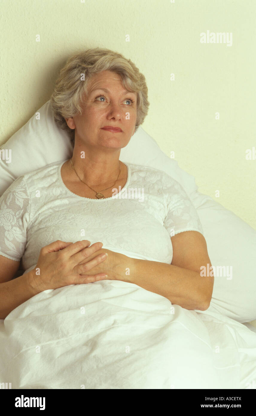 middle age woman lying in bed looking worried Stock Photo Alamy