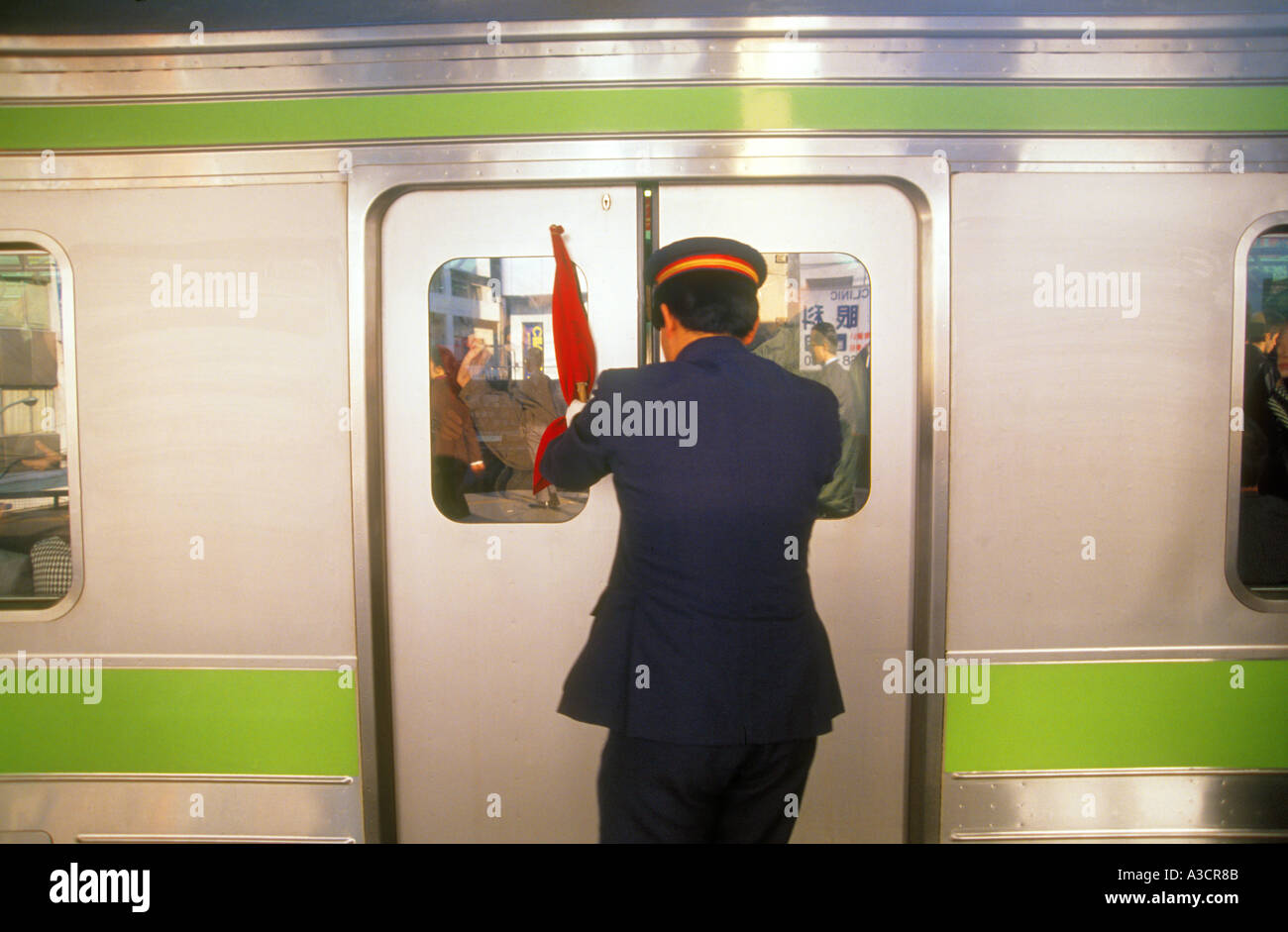 Tokyo Shinjuku Cho Line rushhour busy scene. Pusher pushing commuter passenger into train wagon. Stock Photo