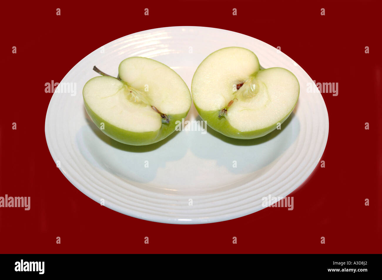 Green Apple Cut In Half On A White Plate Stock Photo Alamy