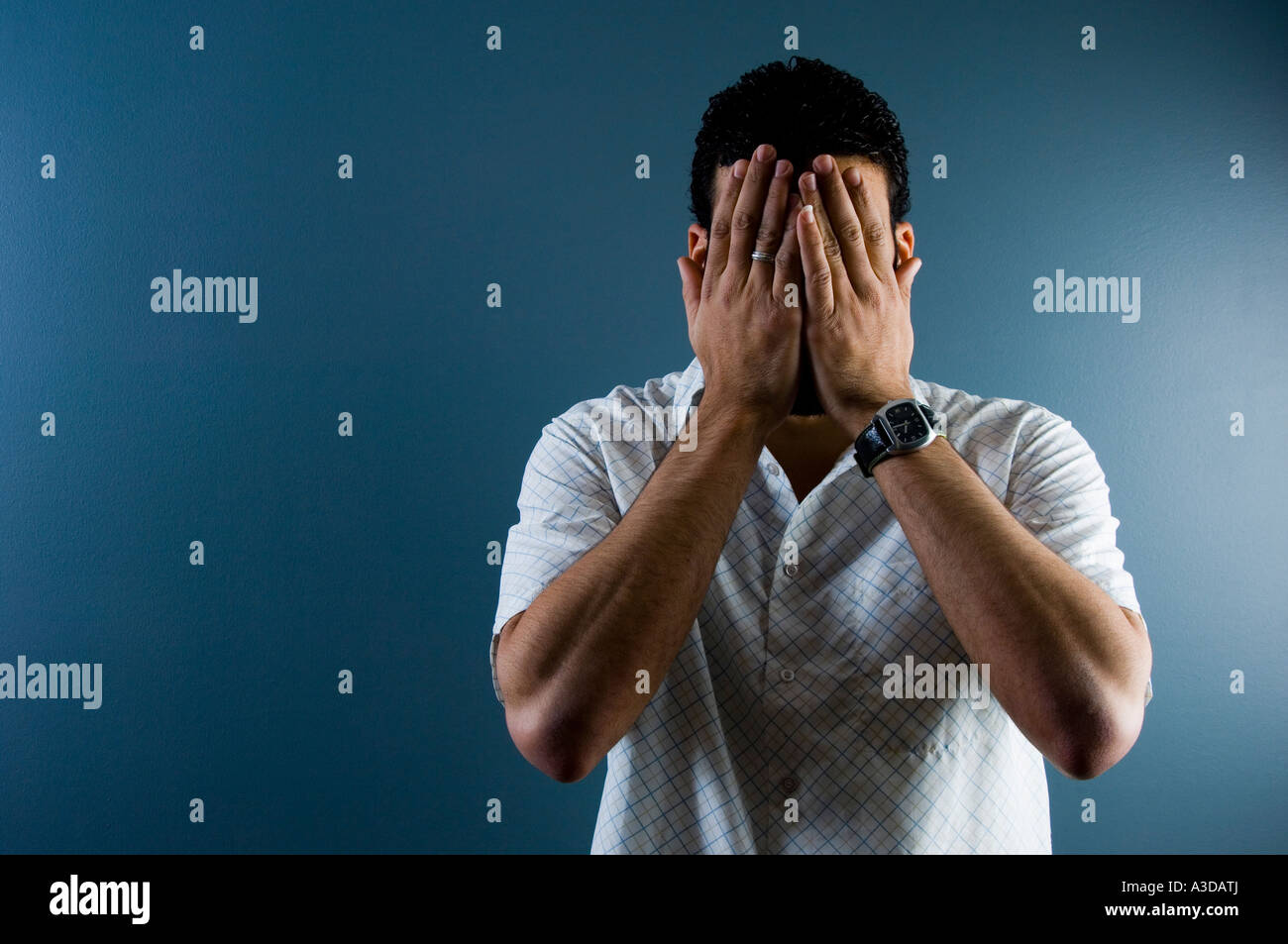 Contemporary image of a man hiding his face indoors Stock Photo