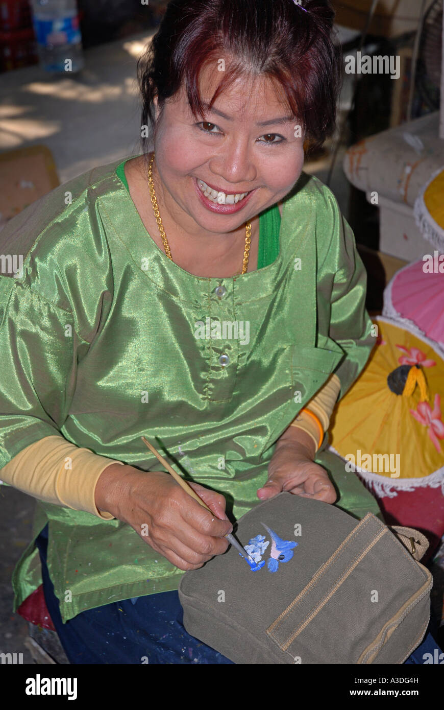 Friendly Thai woman painting a design onto a canvas bag Handicraft factory Chiang Mai Thailand Stock Photo