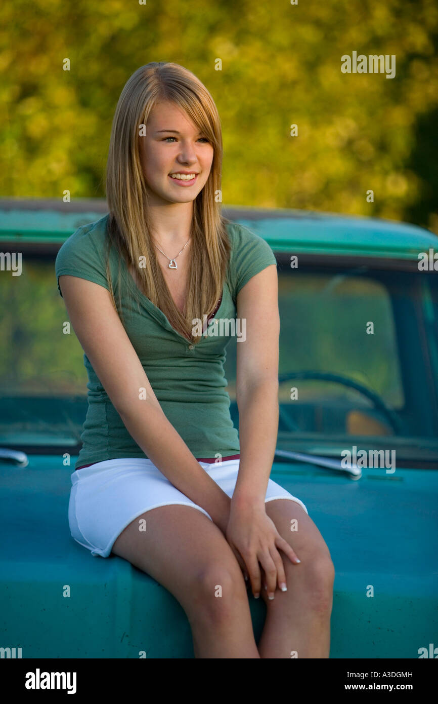 Young woman sits on hood of old truck Stock Photo - Alamy