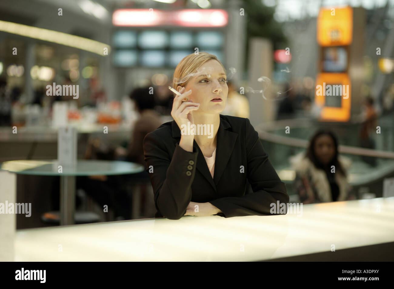 Young woman smoking at an airport café Stock Photo