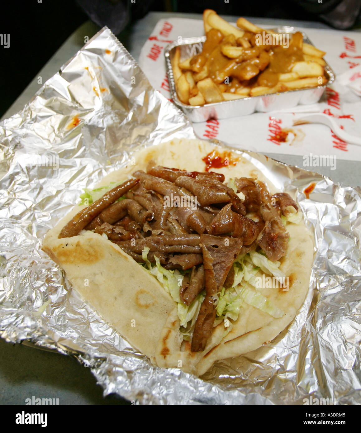 Greasy Donner Kebab in pitta bread with chilli sauce and chips and curry sauce Stock Photo Alamy