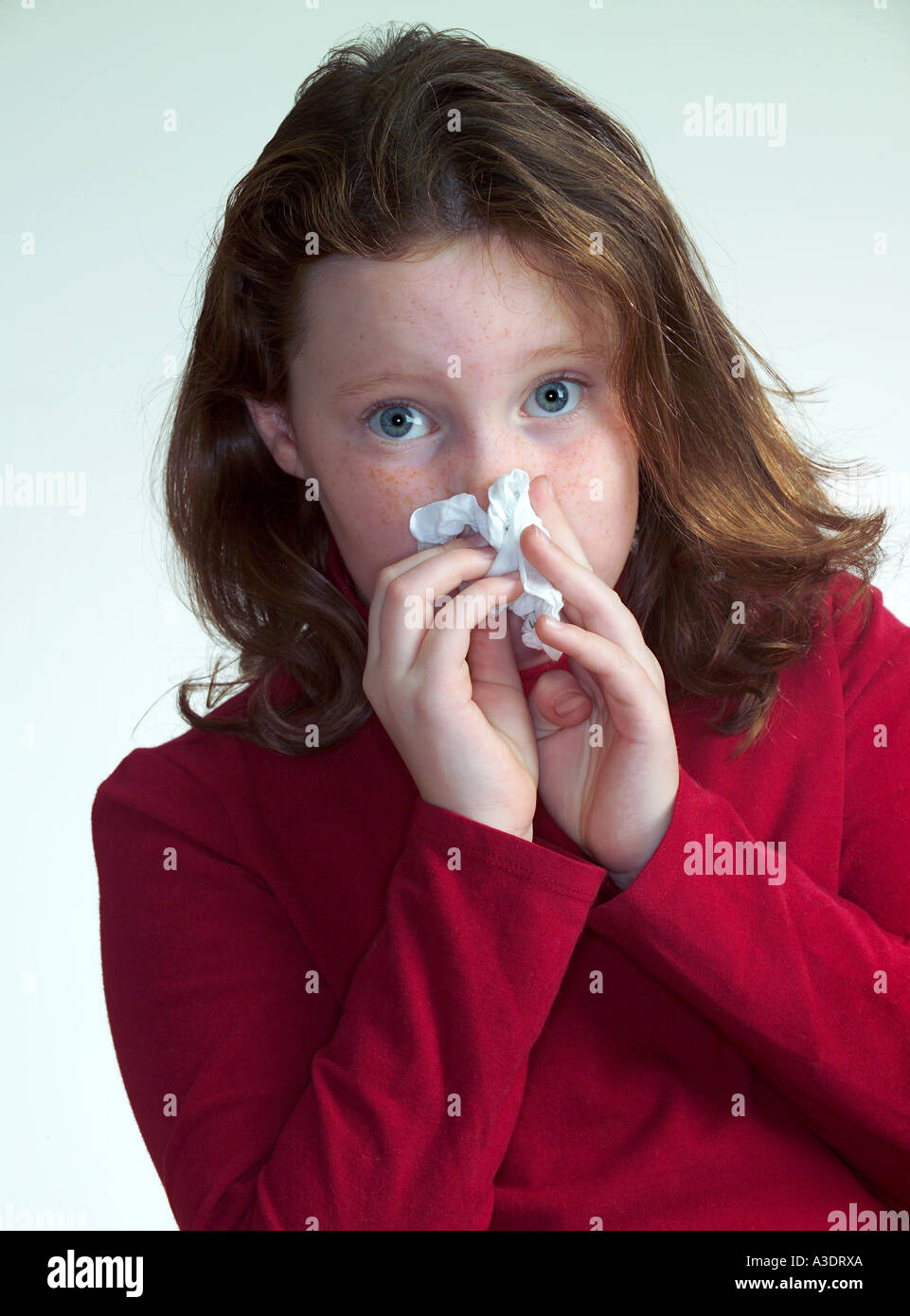 Girl blowing her nose in a tissue, studio Stock Photo Alamy