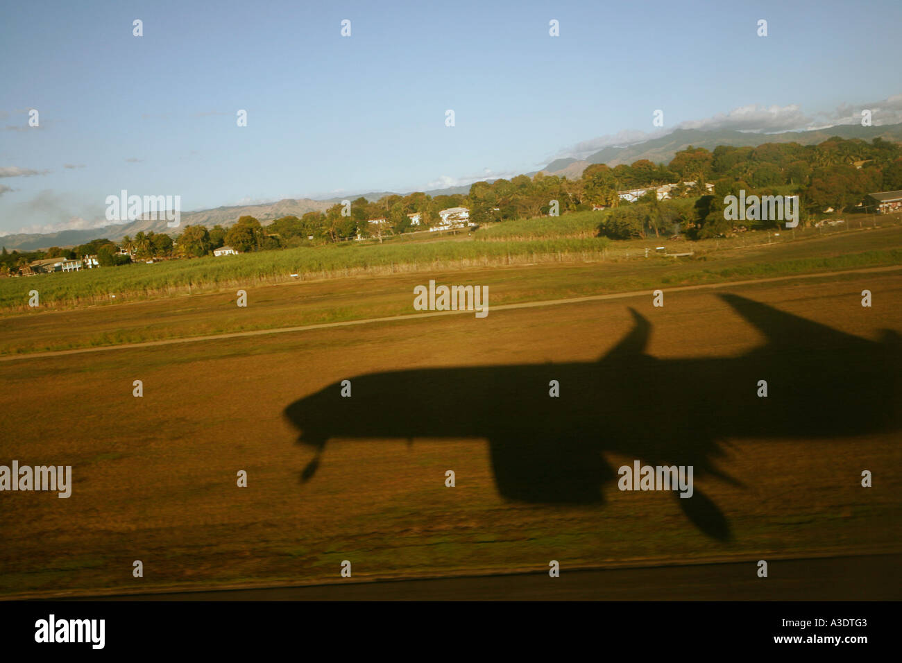 Shadow of Boeing 737-800 airliner coming in to land at Nadi Airport, Fiji, sugar cane fields beside runway Stock Photo