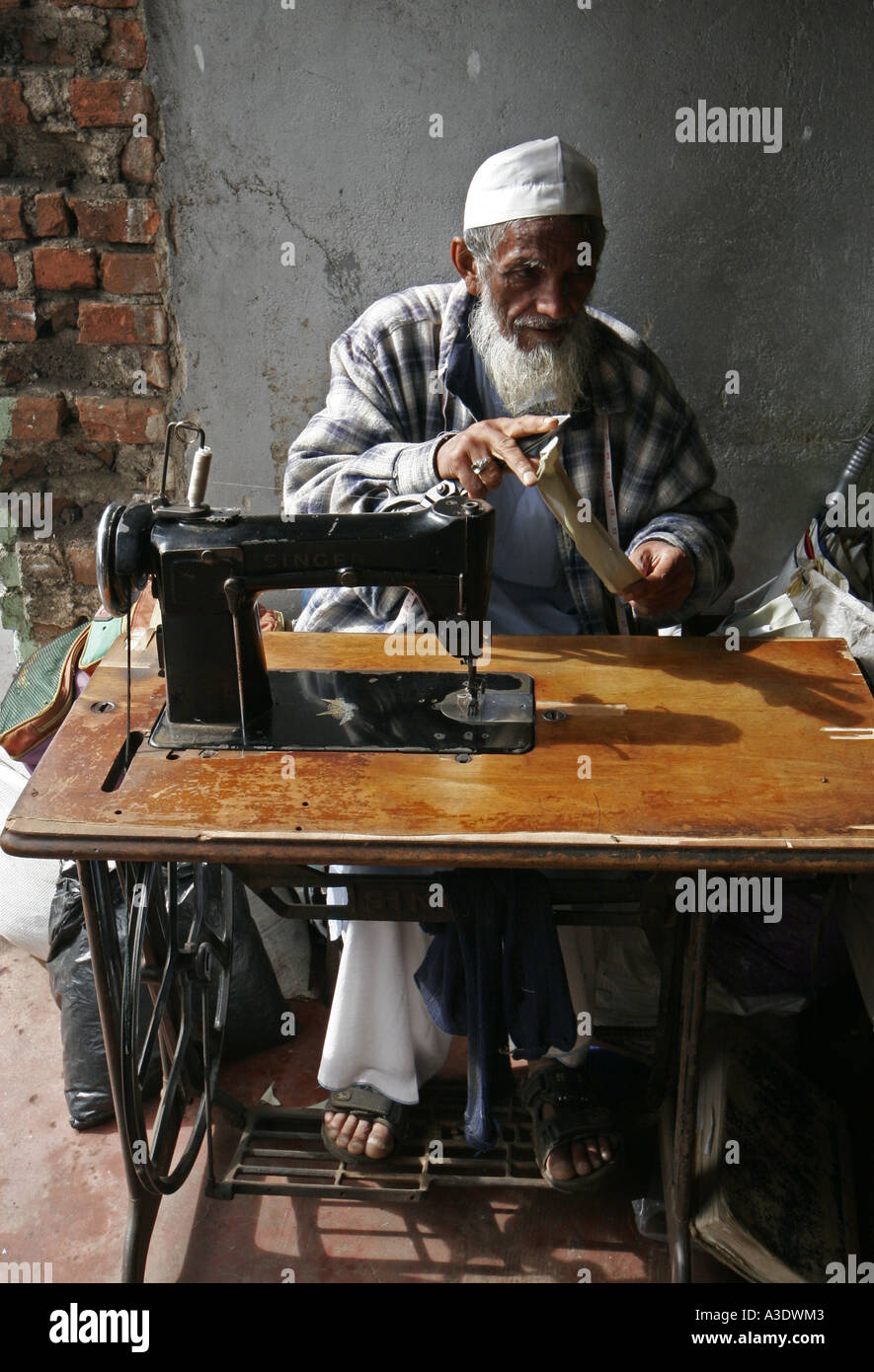 Old Muslim man using old Singer treadleoperated sewing machine on a