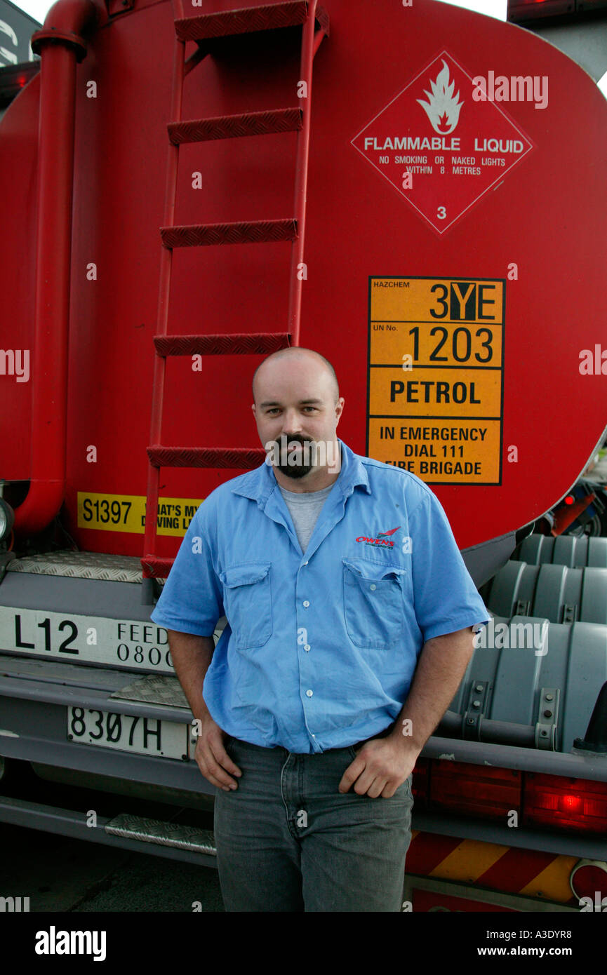 Truck driver standing behind his petrol tanker looking at camera Stock