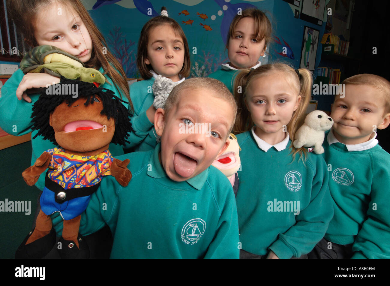 Young children, 6 yrs old, in green school uniforms with puppets in a classroom Stock Photo