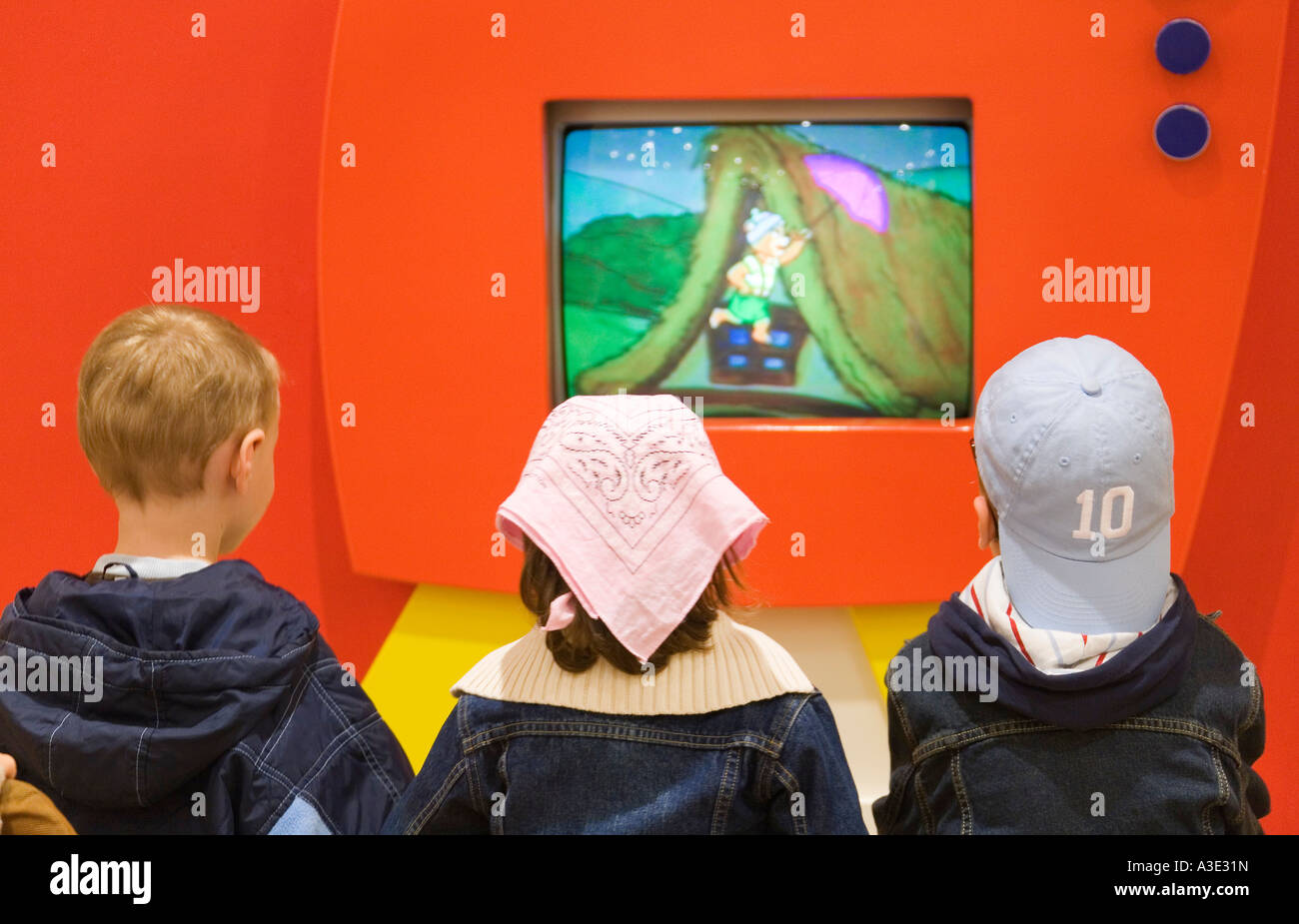Three kids watching an animated film in a shopping mall Stock Photo