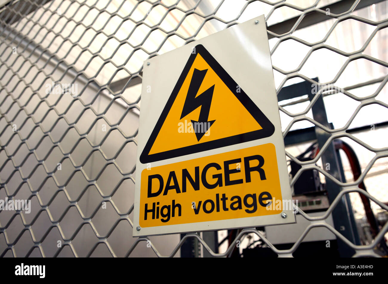 Warning sign "Danger High voltage" attached to steel mesh fence Stock Photo