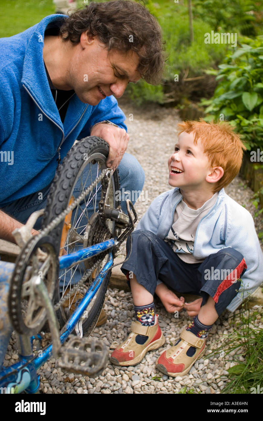Father helps his son reparing his bicycle Stock Photo