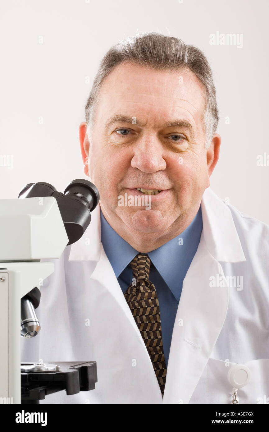 Researcher sits with his microscope, a powerful tool used to magnify research subjects or to make a diagnosis. Stock Photo