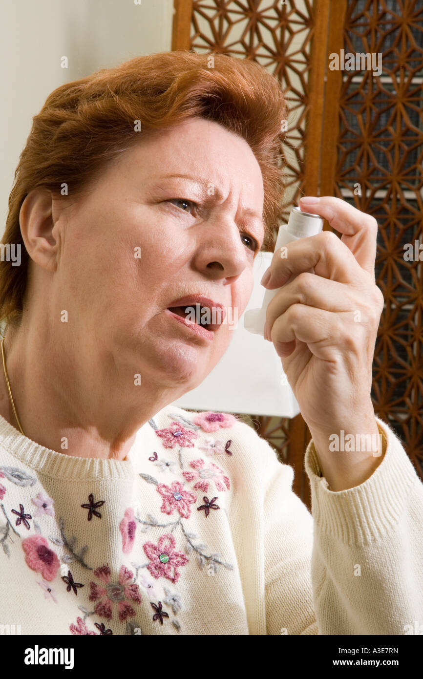 Woman using a bronchial dialator or inhaler (puffer) to relieve asthma symptons Stock Photo