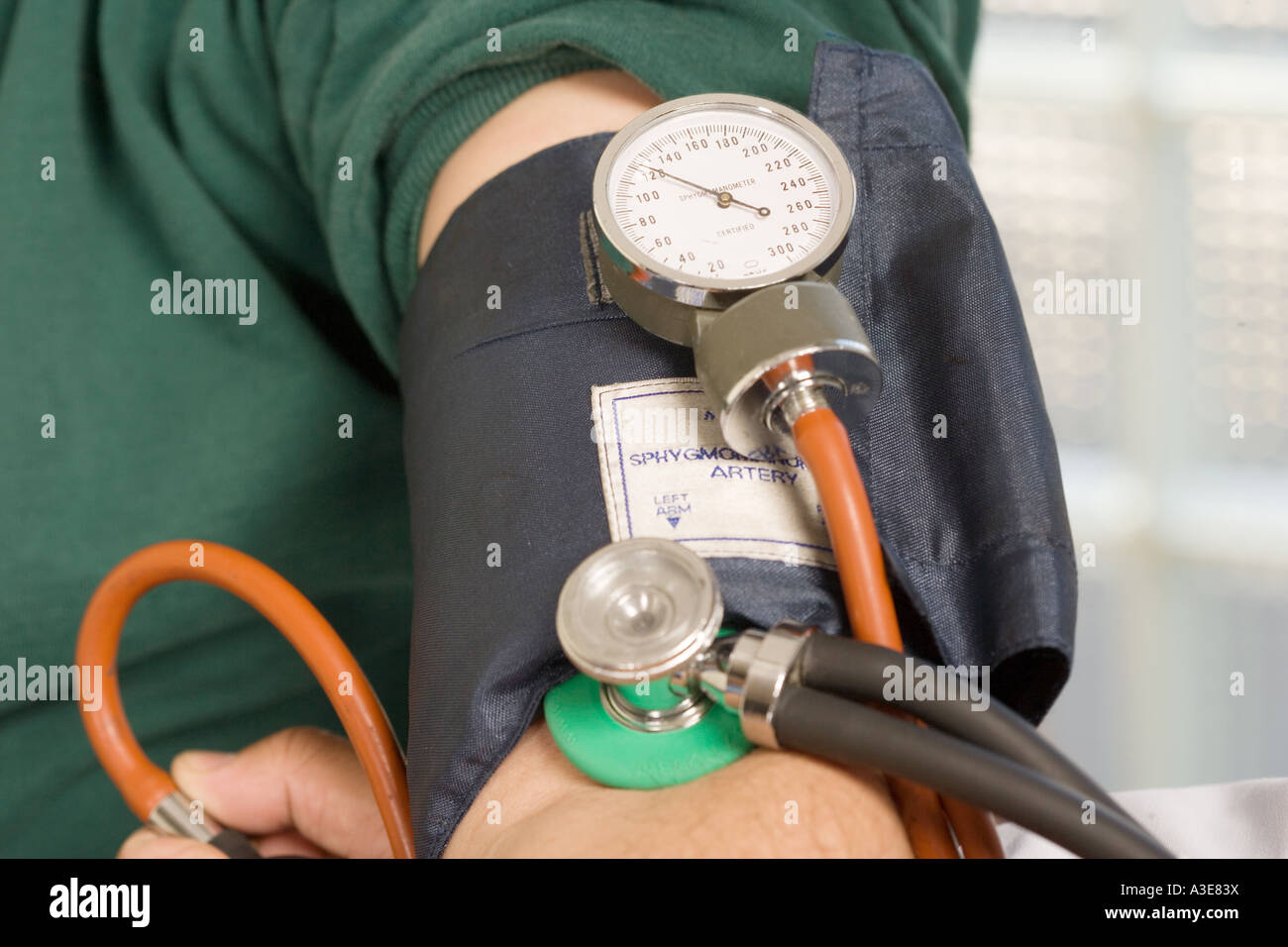 Blood Pressure dial (Sphygmometer) on patients cuff during a blood pressure exam. Stock Photo