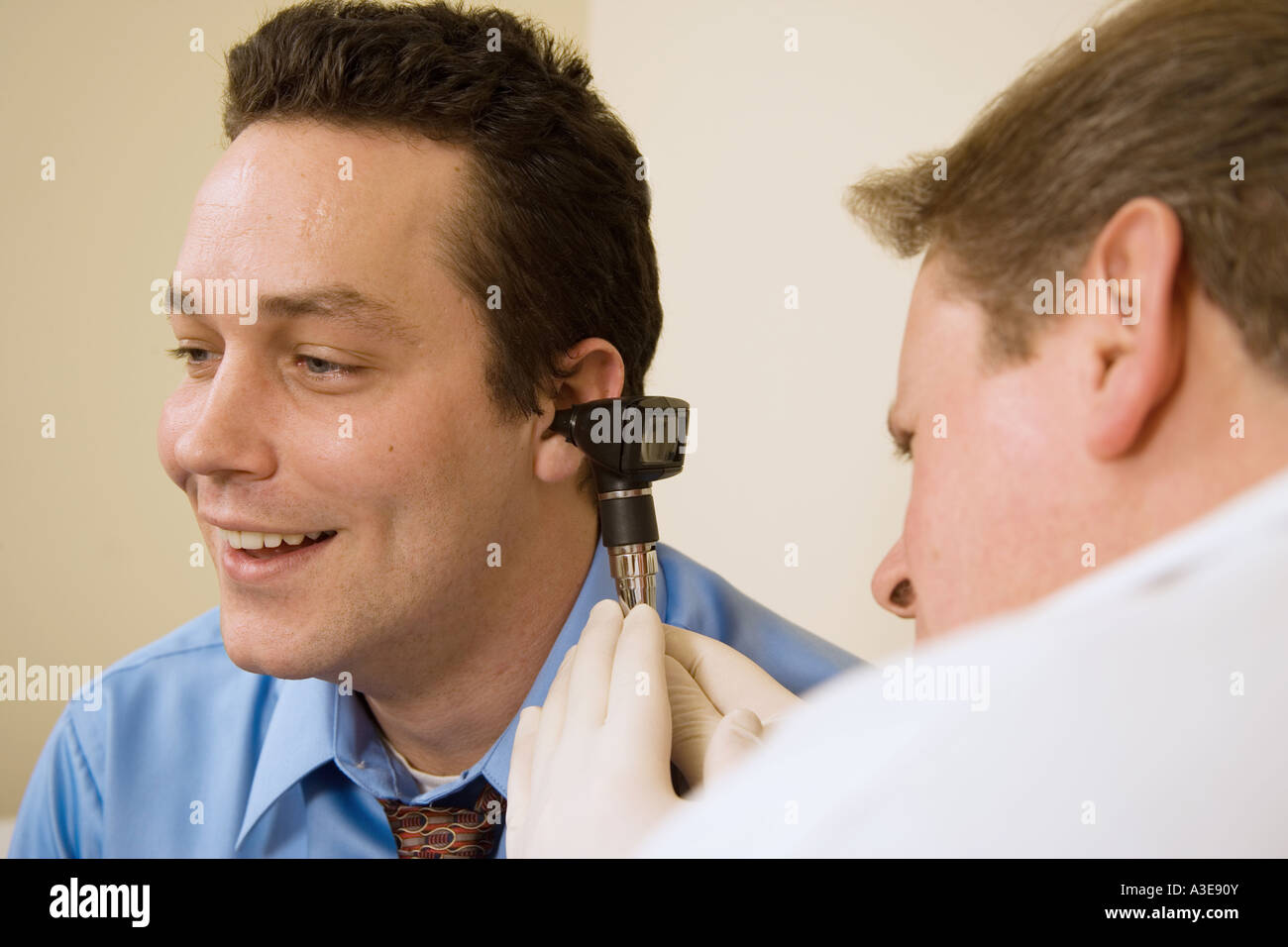Male physician uses an otoscope to check the ear of his patient during