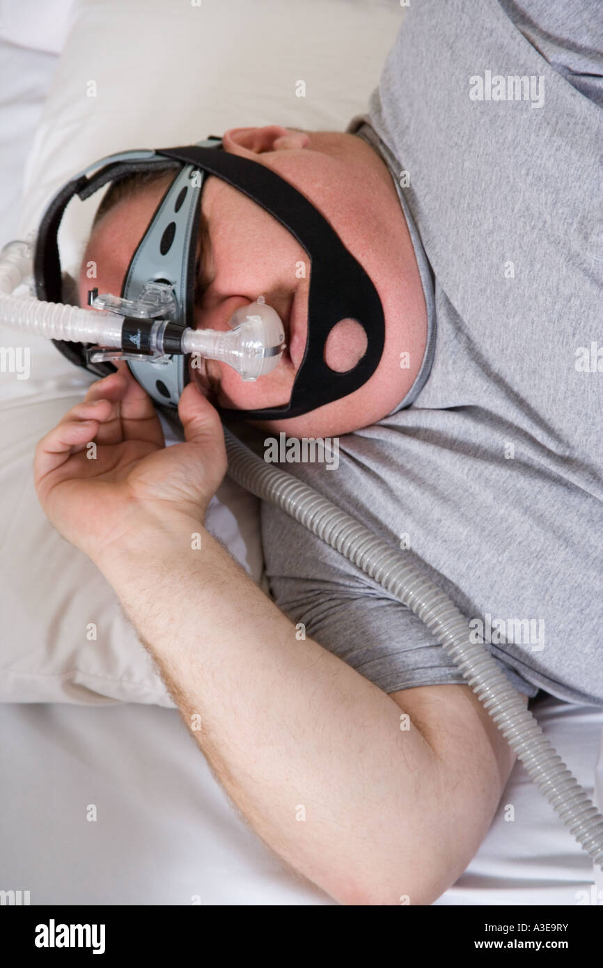 Man wearing CPAP machine to help him breathe and sleep. Stock Photo