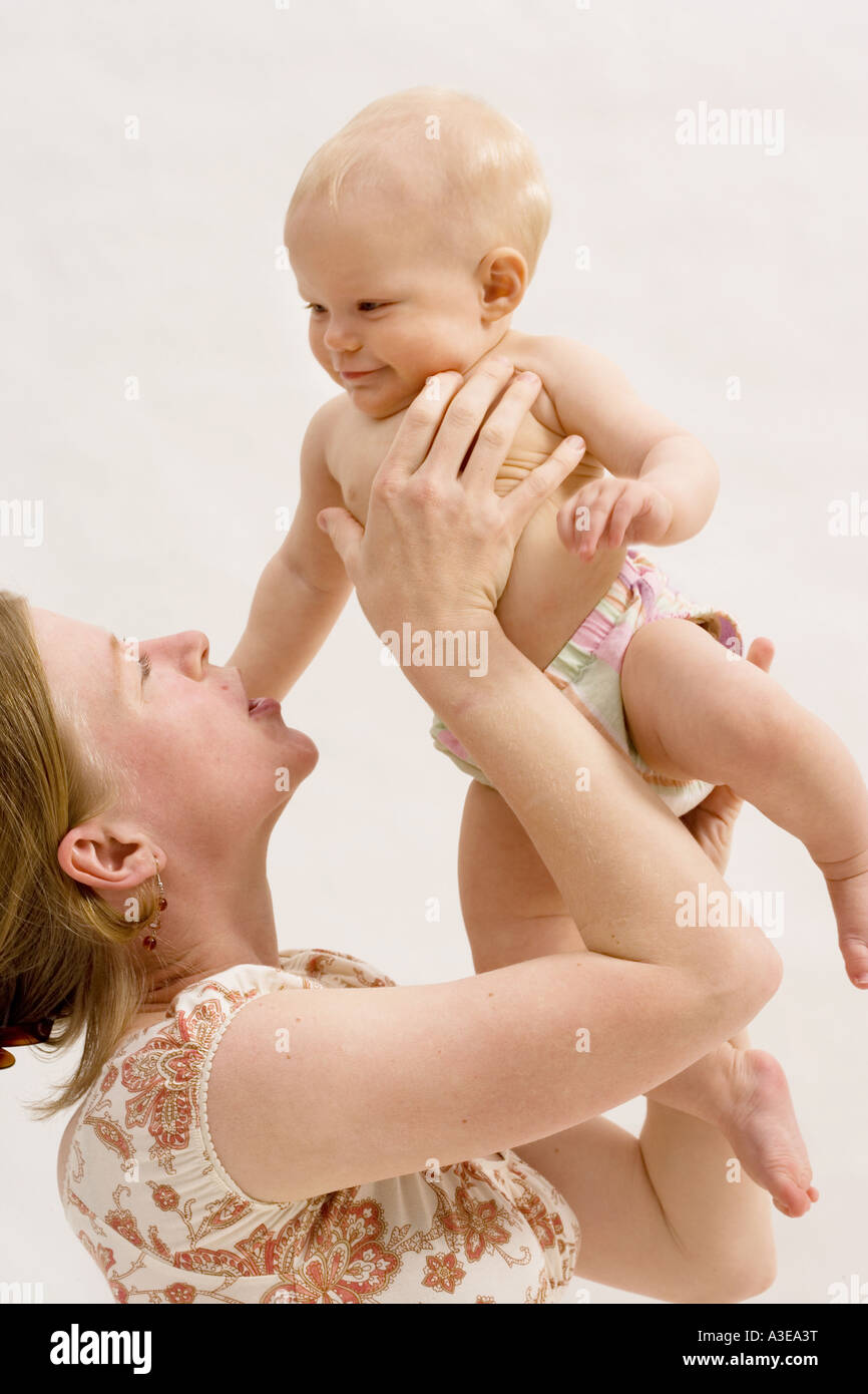 8 month old baby girl is held up by her mother. Stock Photo