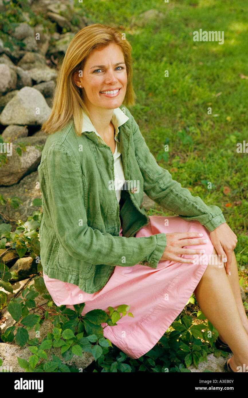Portrait of a mid adult woman sitting on a rock and smiling Stock Photo ...