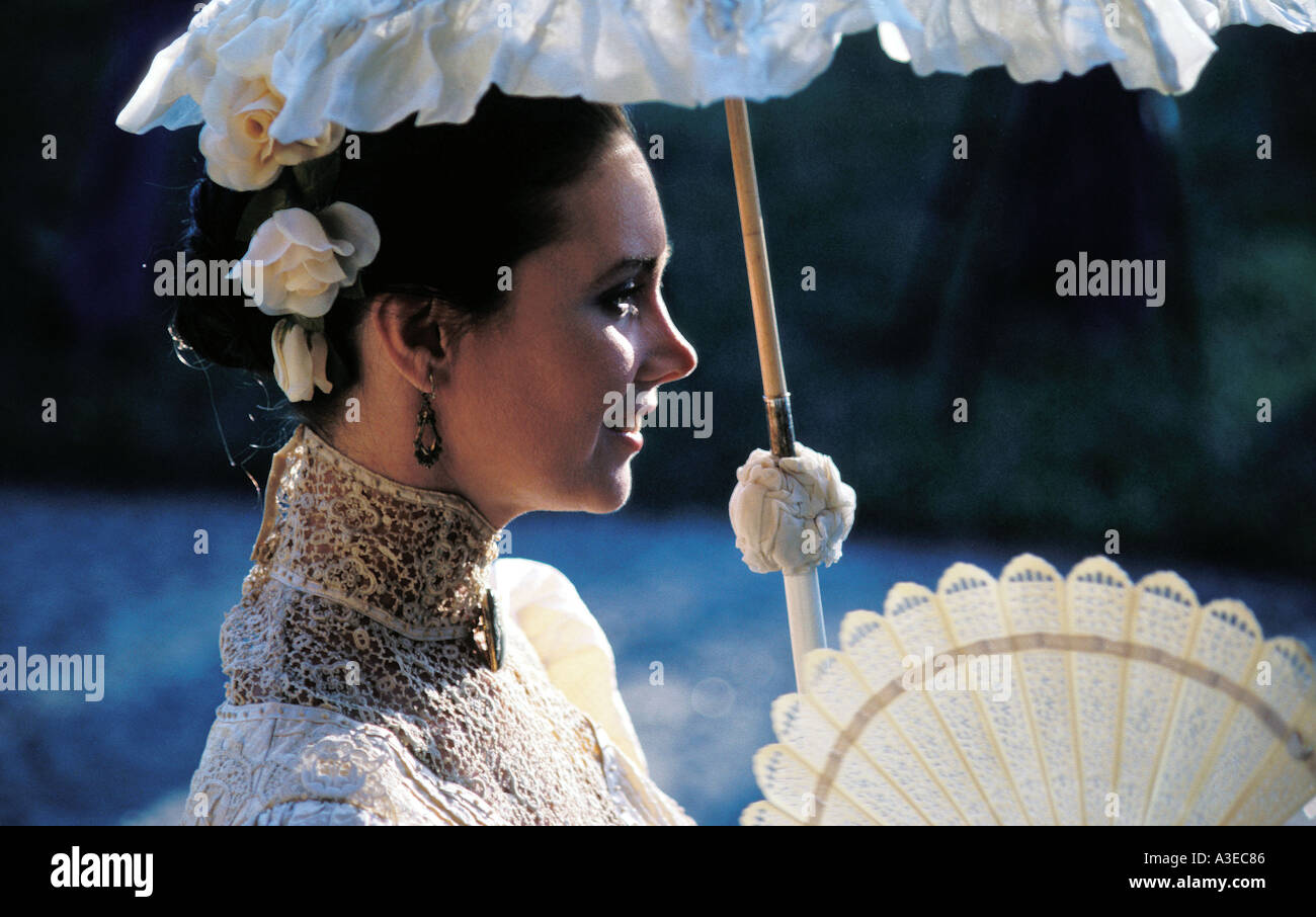 A beautiful woman in a white Victorian dress carries a parasol at ...