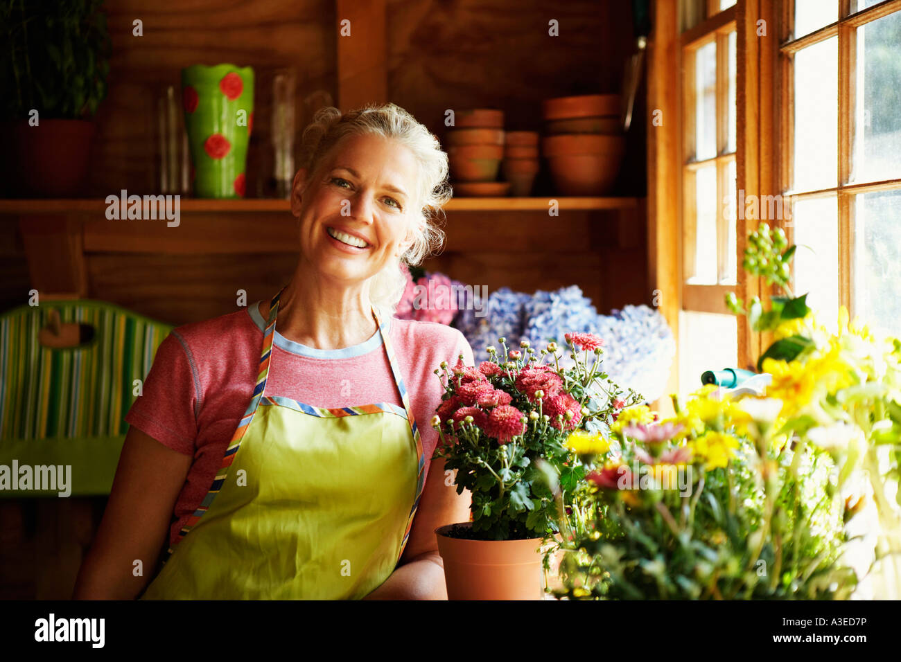 Portrait of a mature woman standing near potted plants Stock Photo - Alamy