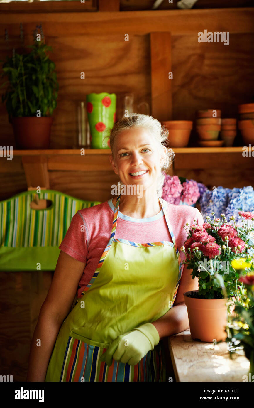 Portrait of a mature woman standing near potted plants Stock Photo - Alamy