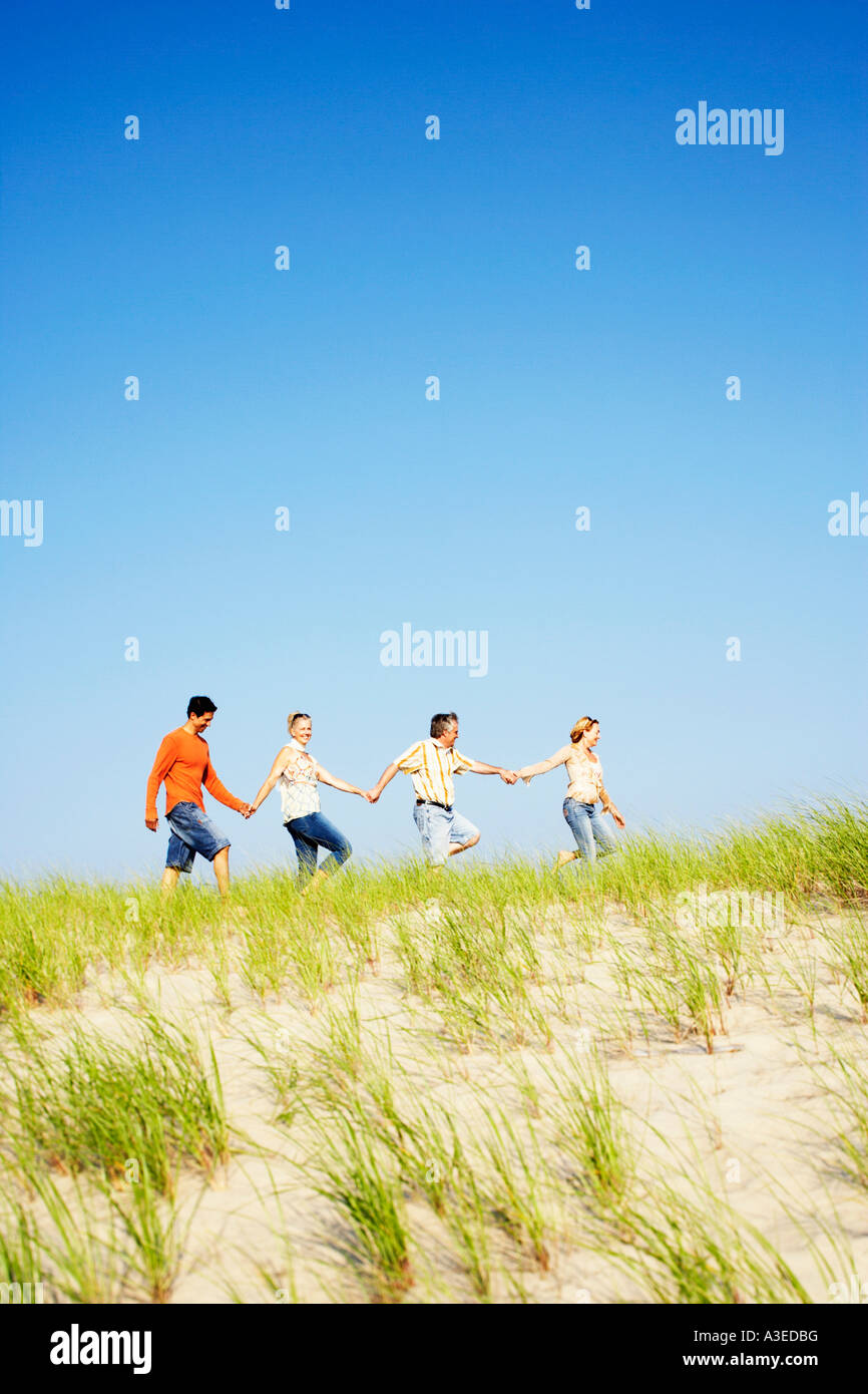 Two mature couples holding hands and walking on the beach Stock Photo