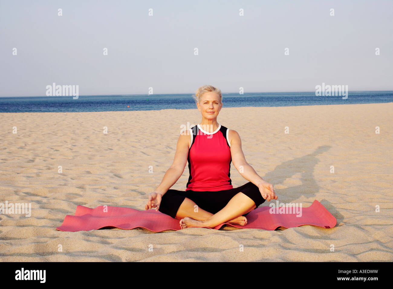 Portrait of a mature woman performing yoga on the beach Stock Photo