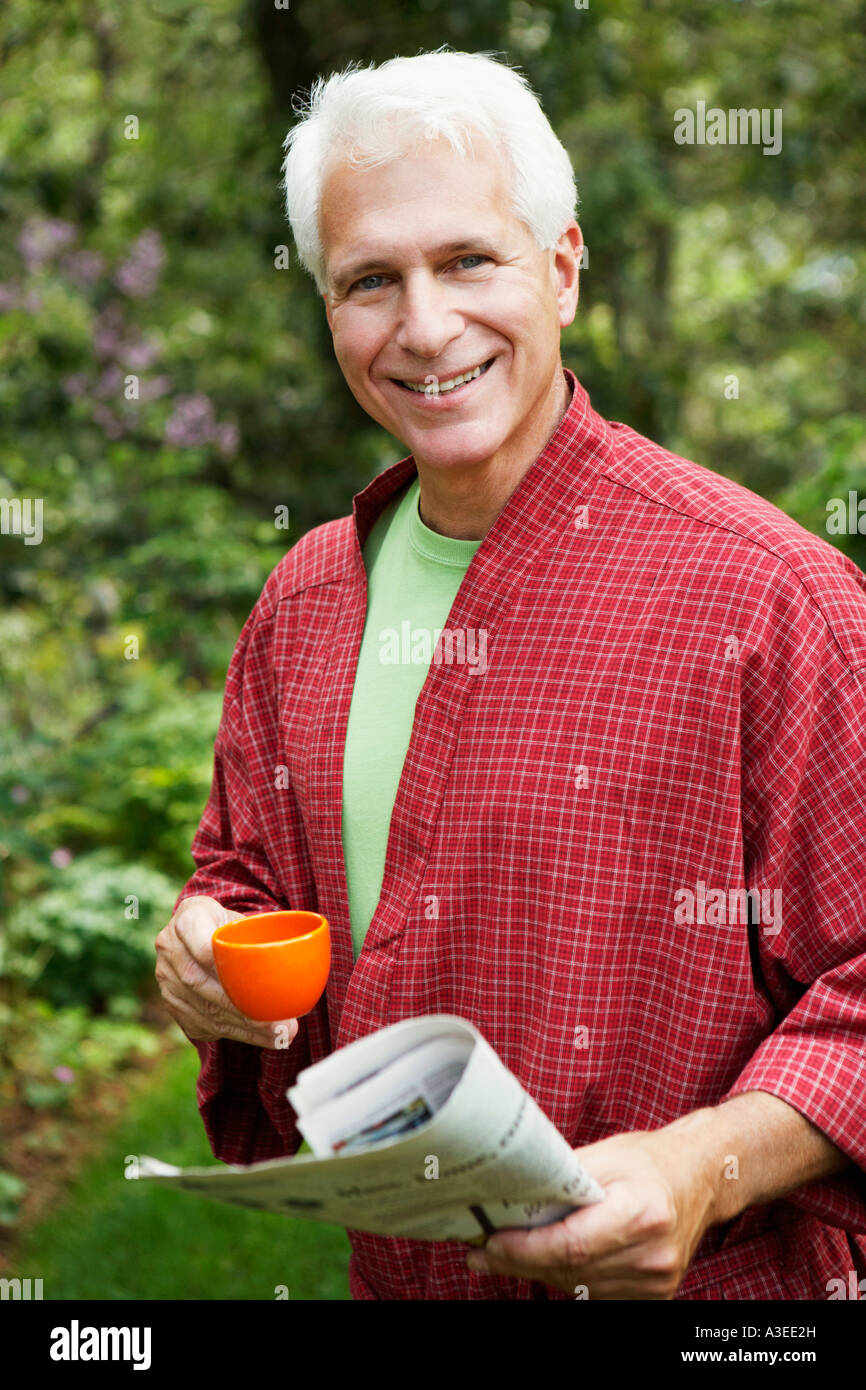 Portrait of a mature man holding a newspaper and a cup of tea Stock