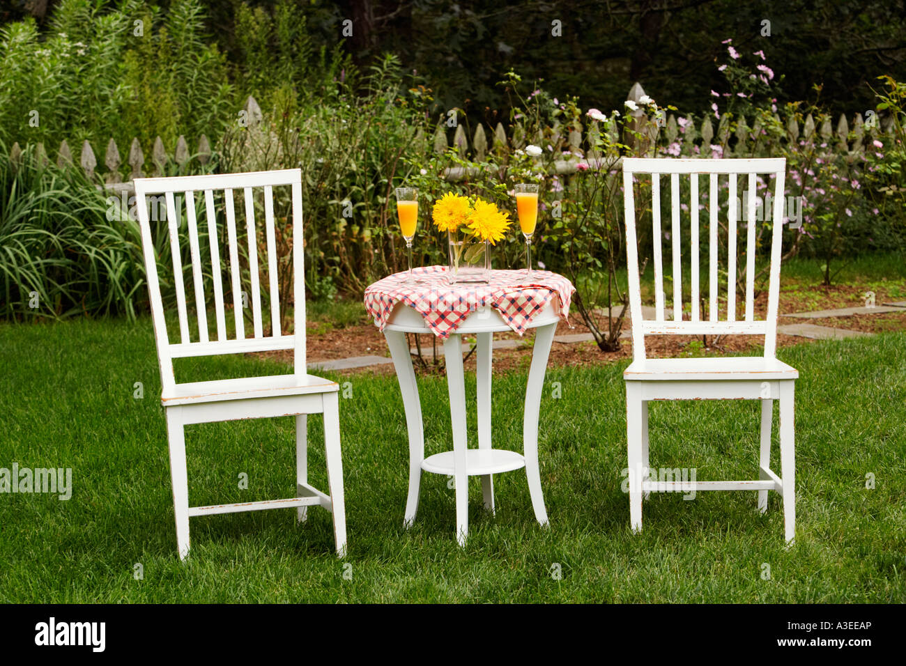 Two chairs and a table in a garden Stock Photo - Alamy