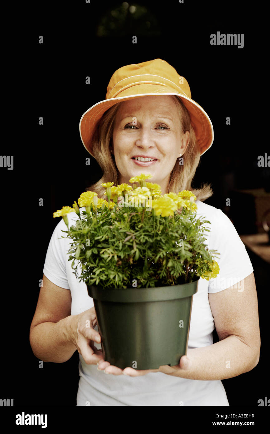 Portrait of a mature woman holding a potted plant and smiling Stock ...
