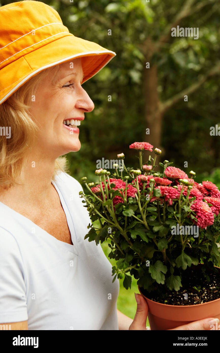 Side profile of a mature woman holding a potted plant and smiling Stock ...