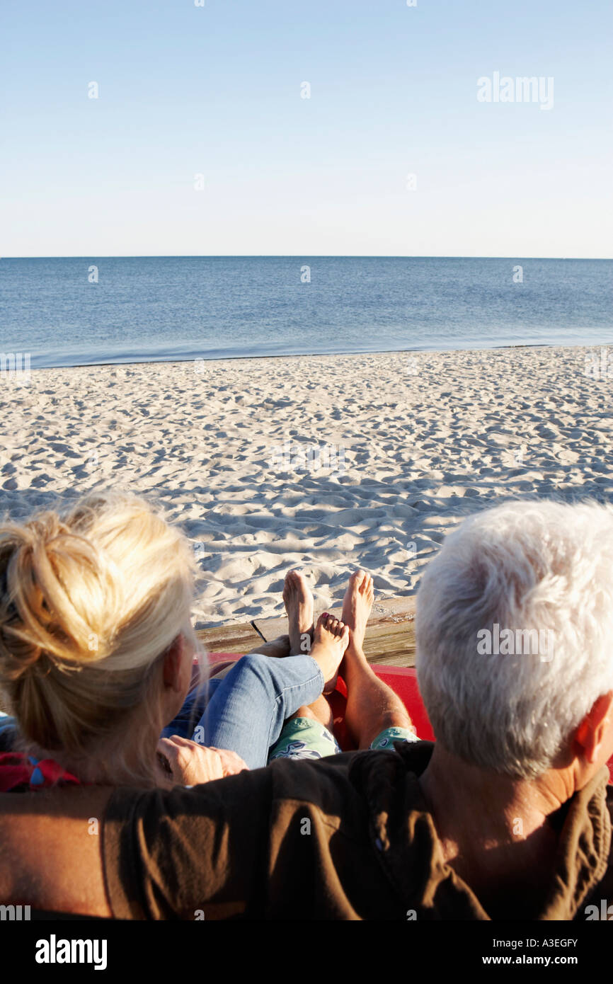 Rear view of a mature couple sitting on the beach Stock Photo - Alamy