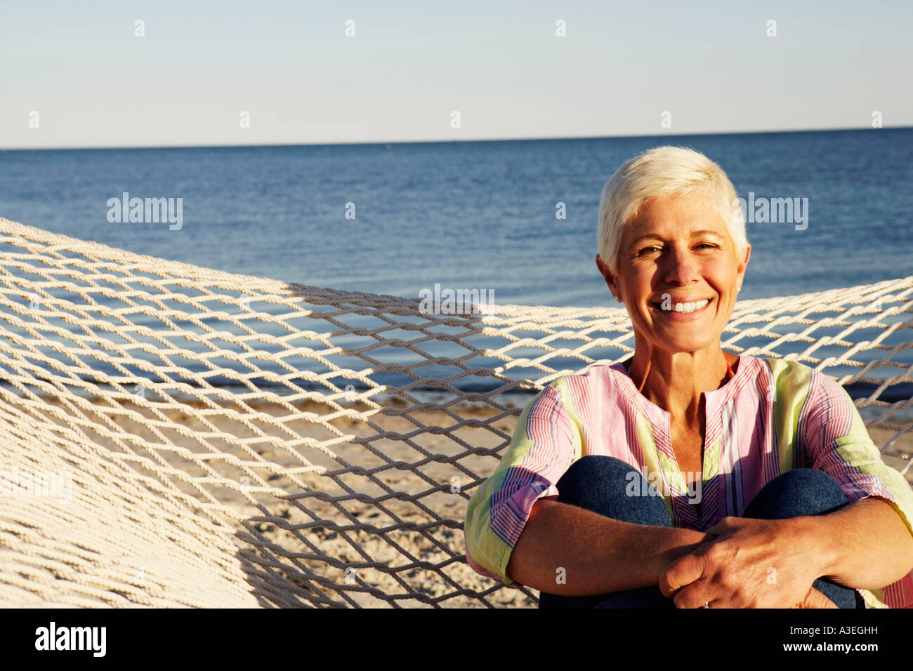 Portrait of a mature woman sitting in a hammock and smiling Stock Photo ...