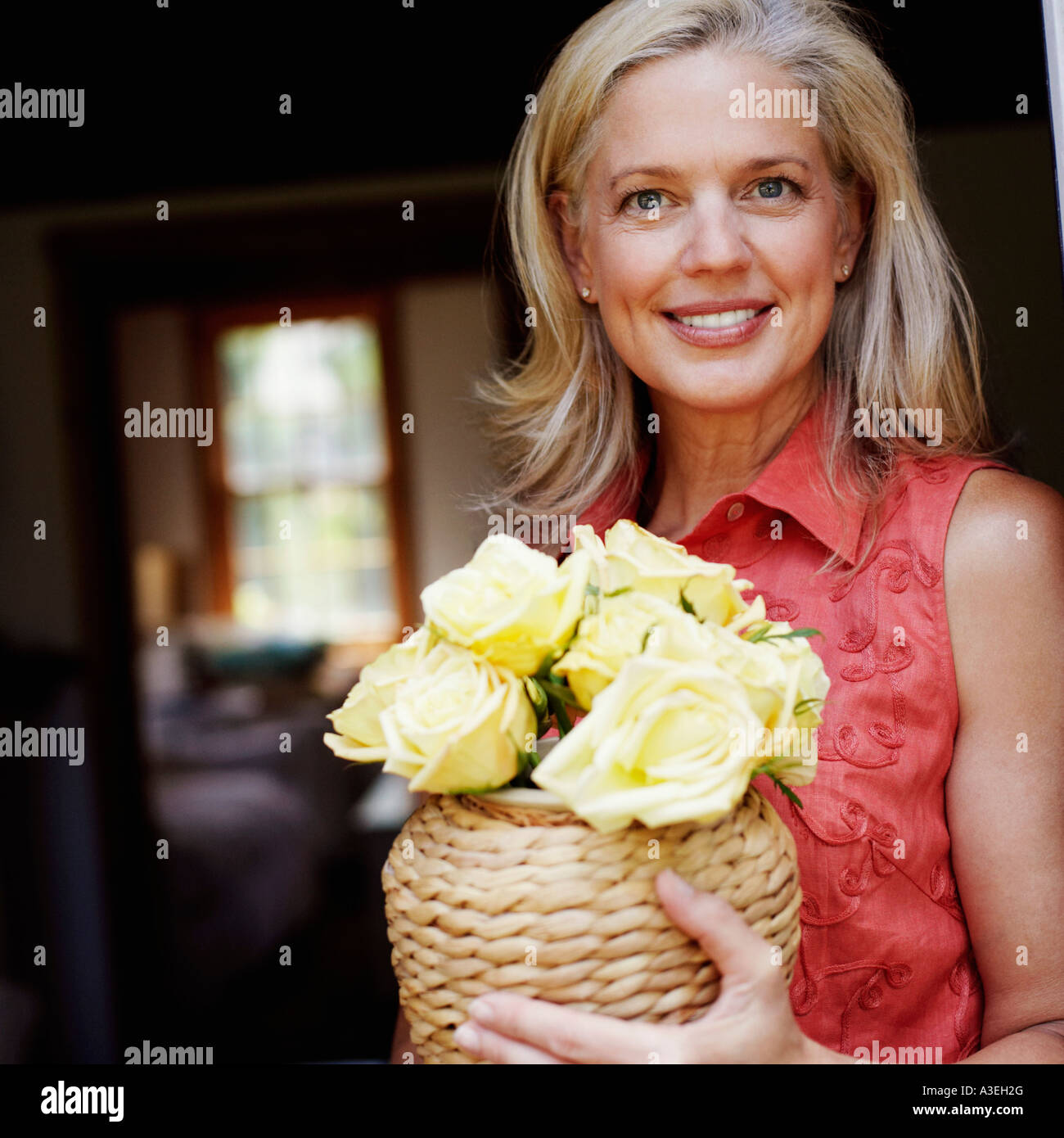 Portrait of a mature woman holding flowers in a vase and smiling Stock ...