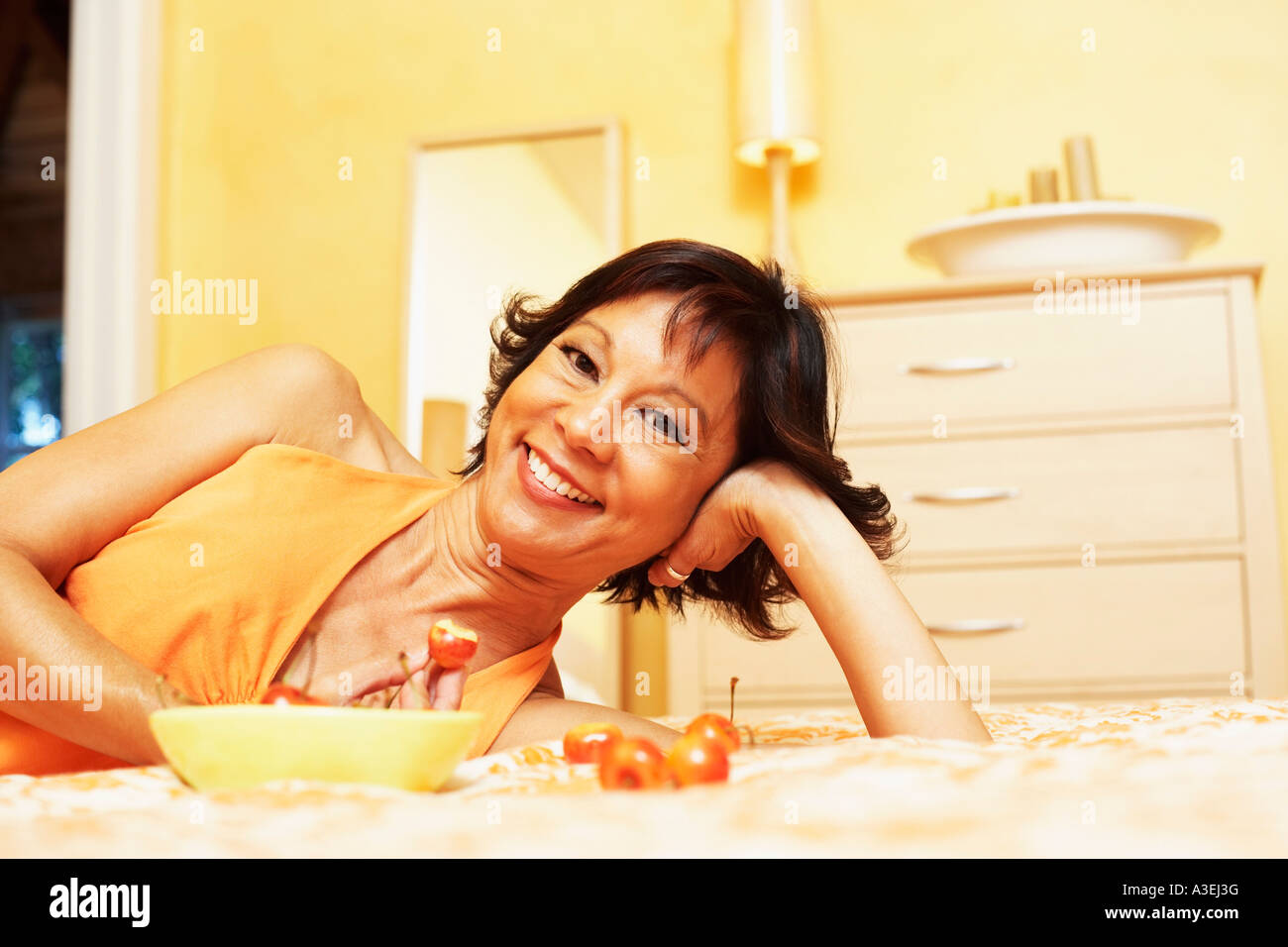 Portrait of a mature woman lying on the bed and smiling Stock Photo - Alamy
