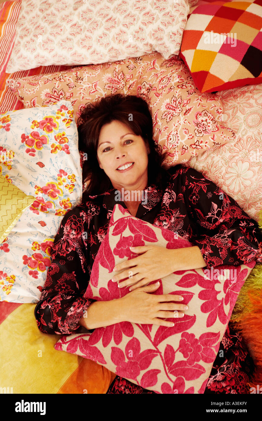 Portrait of a mature woman lying on the bed and smiling Stock Photo - Alamy