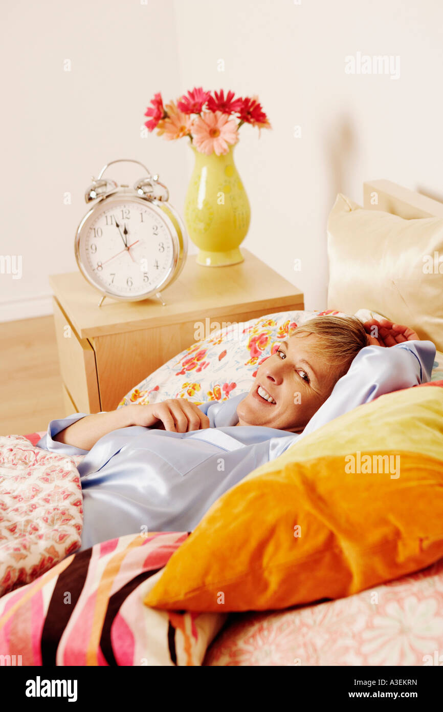 Portrait of a mature woman lying in bed and smiling Stock Photo - Alamy