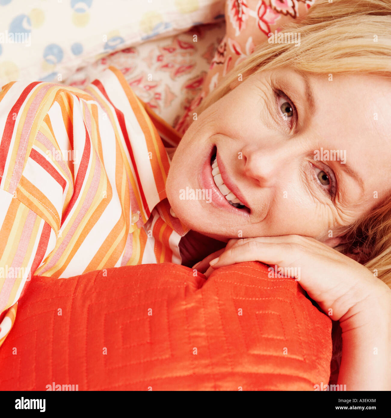 Portrait of a mature woman lying in bed and smiling Stock Photo - Alamy