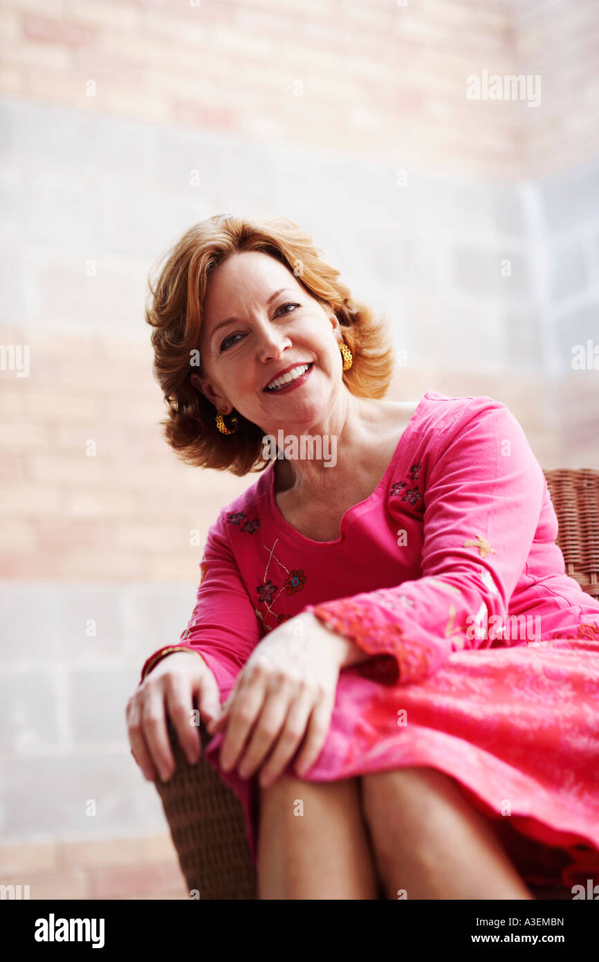 Portrait of a mature woman sitting on a chair and smiling Stock Photo ...