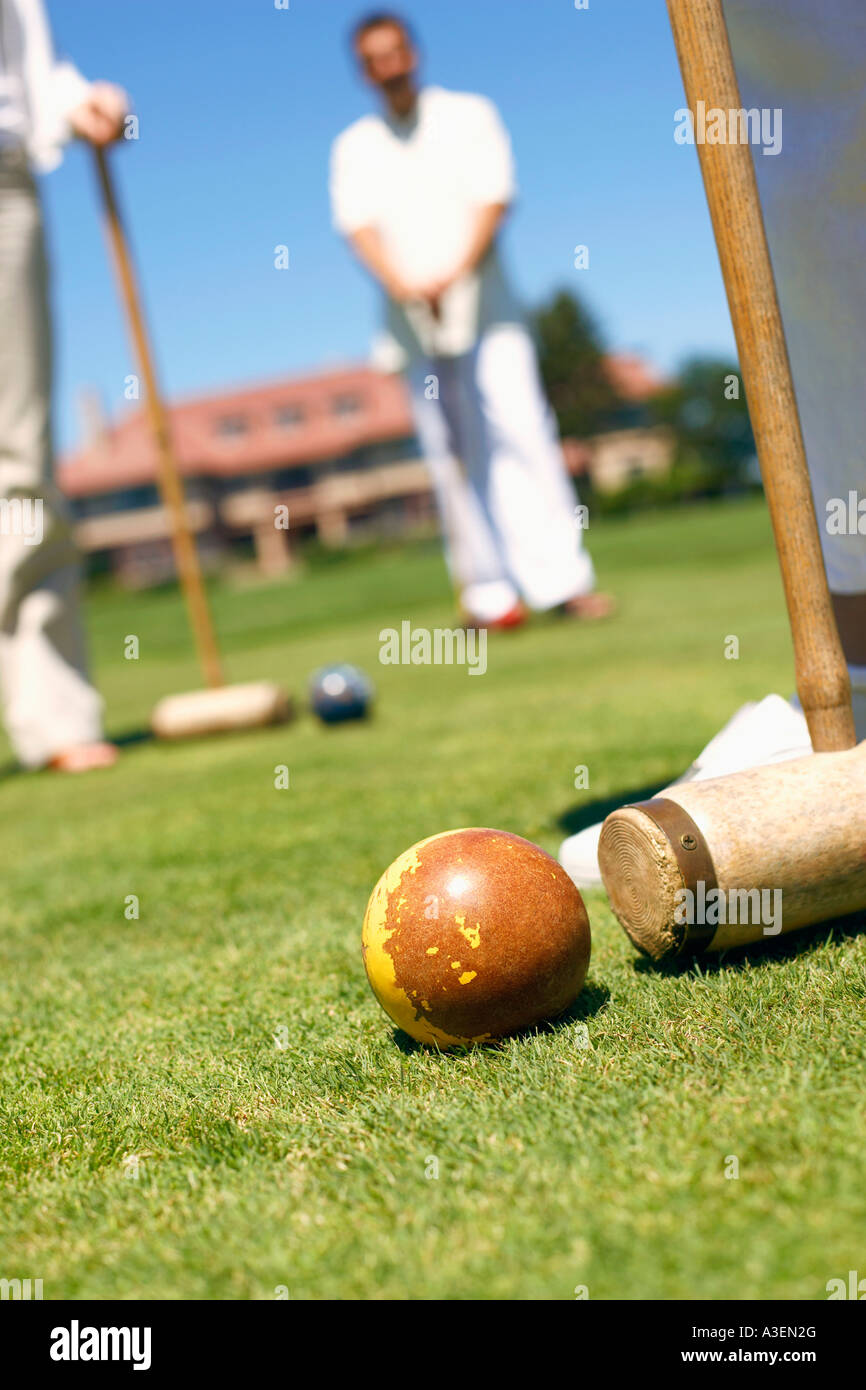 Three people holding croquet mallets in a playing field Stock Photo Alamy