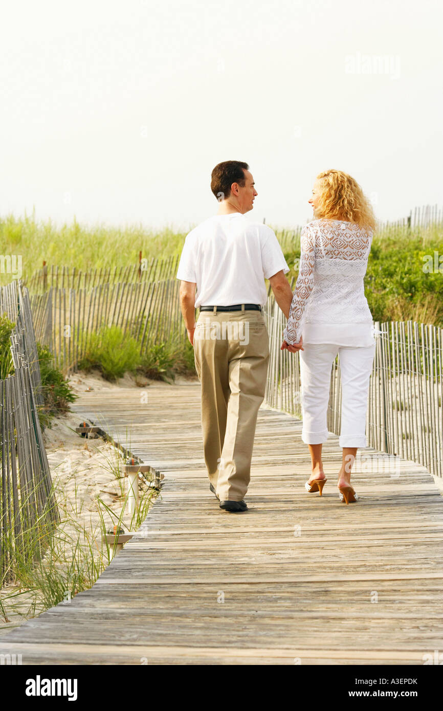 Rear view of a man and a woman walking on a boardwalk Stock Photo - Alamy