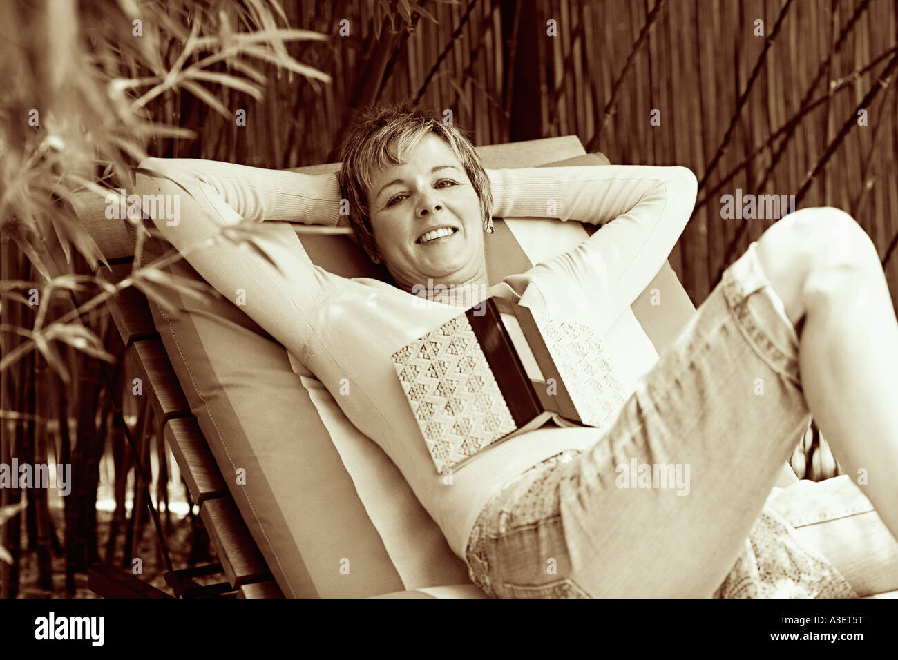 Portrait of a mature woman reclining on a lounge chair Stock Photo - Alamy
