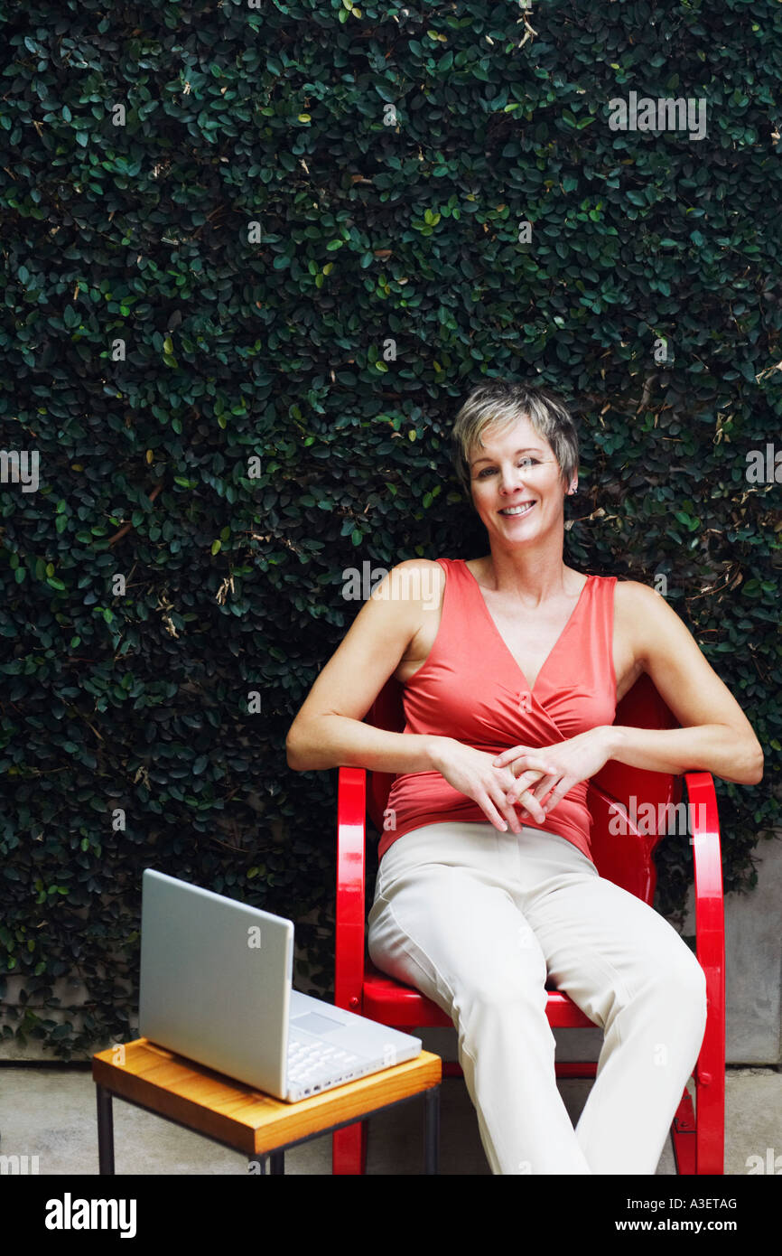 Portrait of a mature woman sitting on a chair and smiling Stock Photo ...