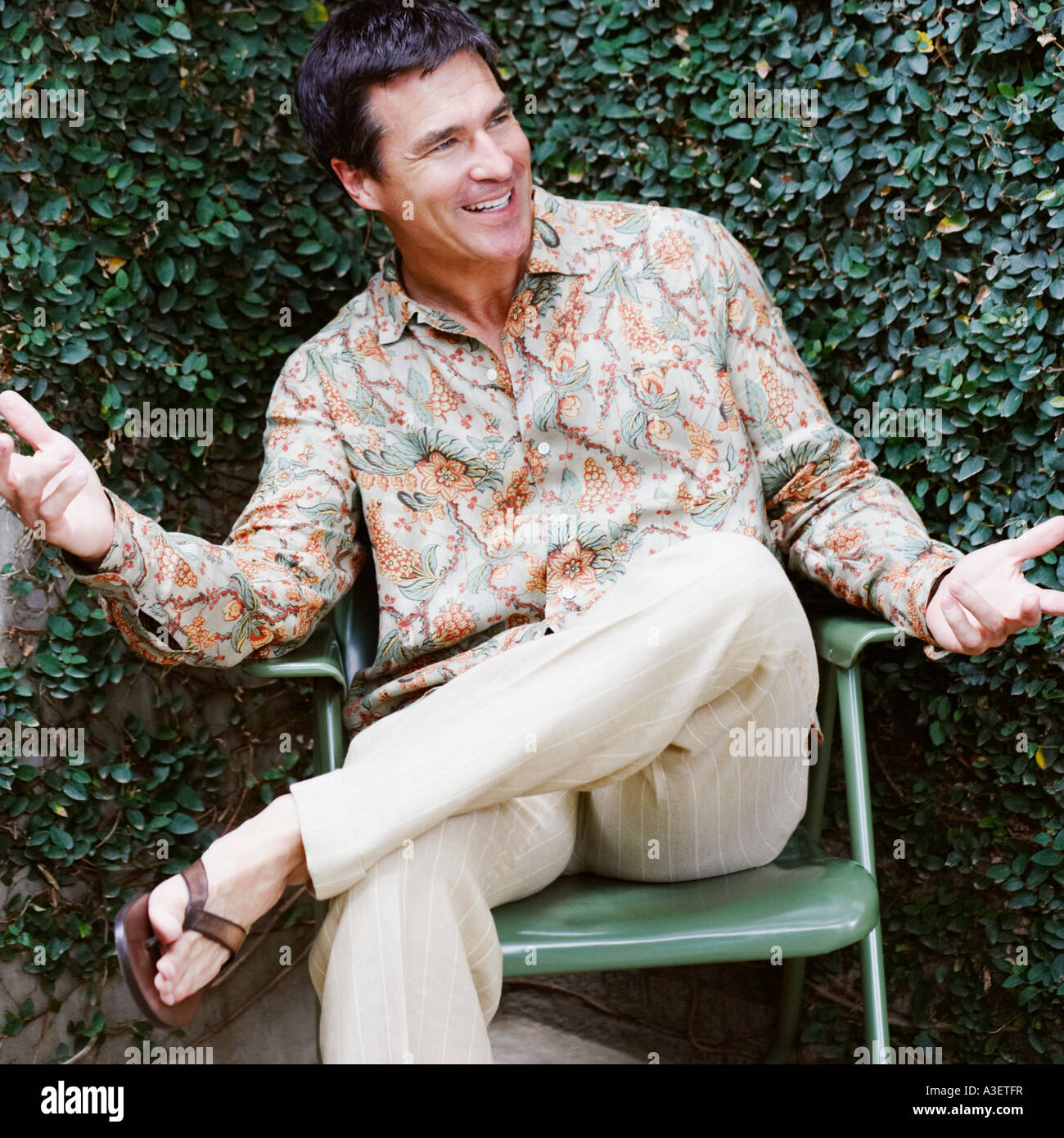 Mature man sitting on a chair and smiling Stock Photo - Alamy
