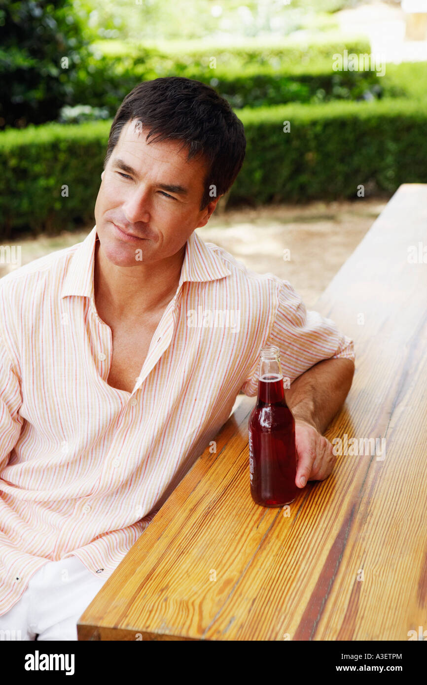 Close-up of a mature man sitting at a table and holding bottle of red wine Stock Photo