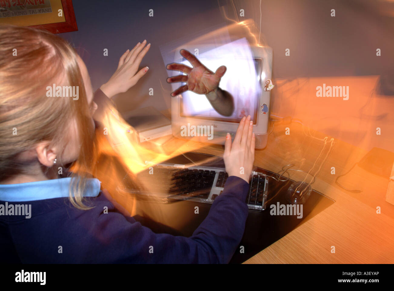 Young girl on a computer with a hand coming from the screen as if not being able to escape bullying UK Stock Photo