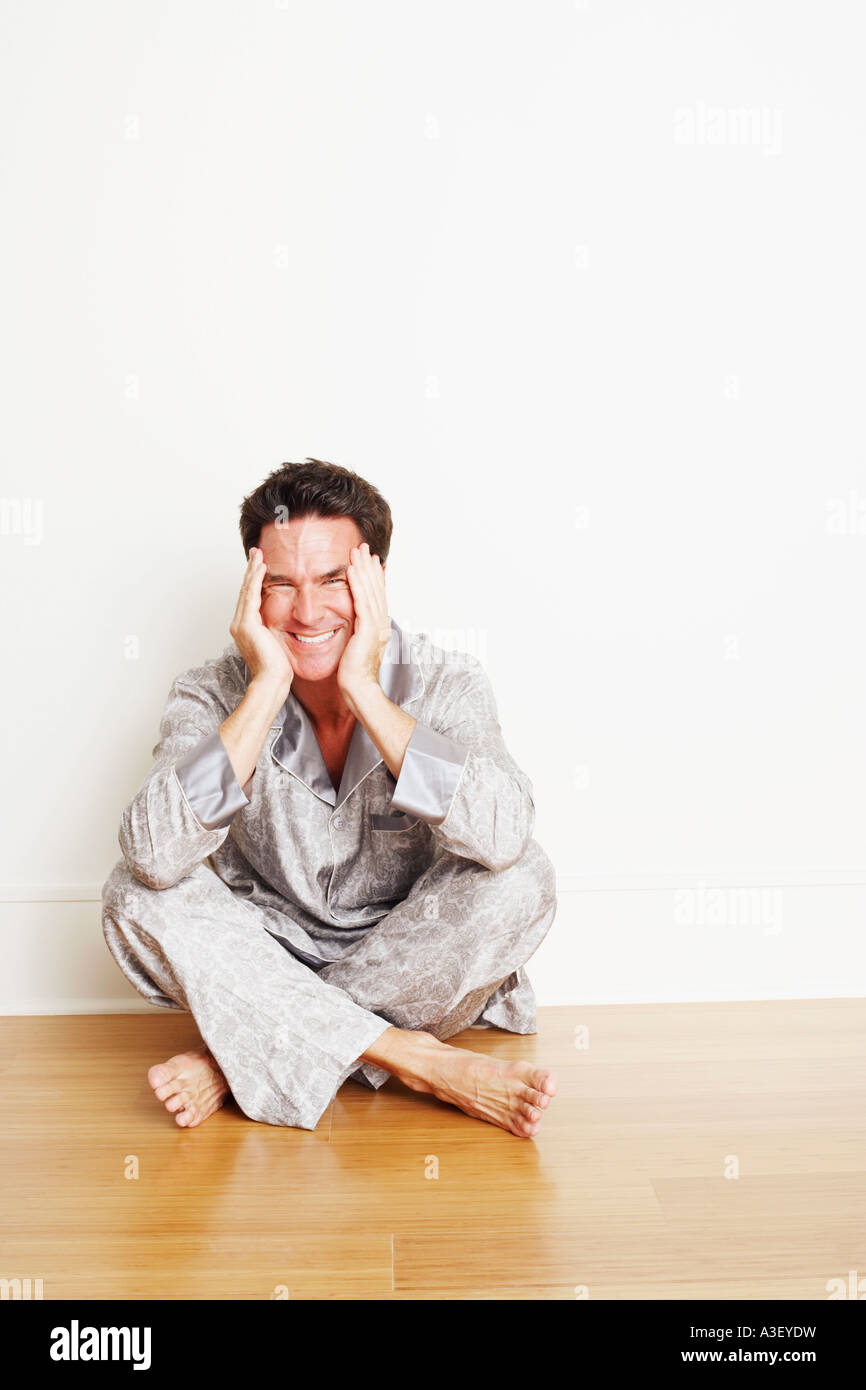 Portrait of a mature man sitting cross-legged on the floor and making a ...