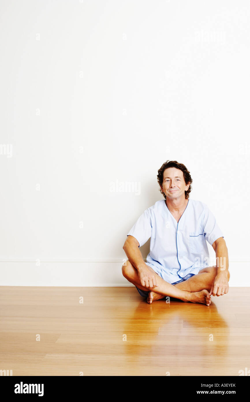 Portrait of a mature man sitting cross-legged on the floor and smiling ...